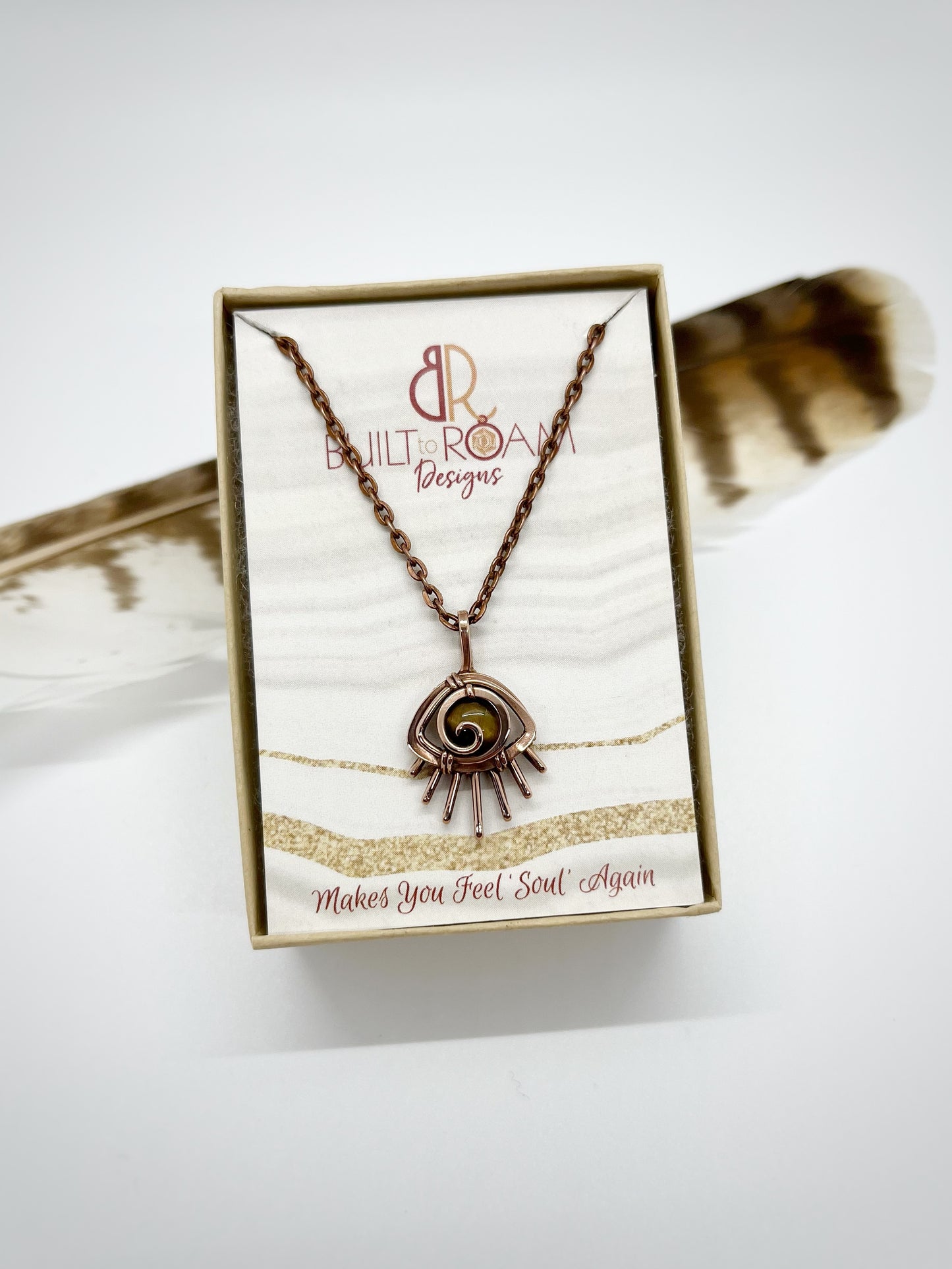 Copper eye-shaped pendant necklace with a golden Tiger’s Eye gemstone in a Built to Roam Designs jewelry box against a white background - front view - Guardian