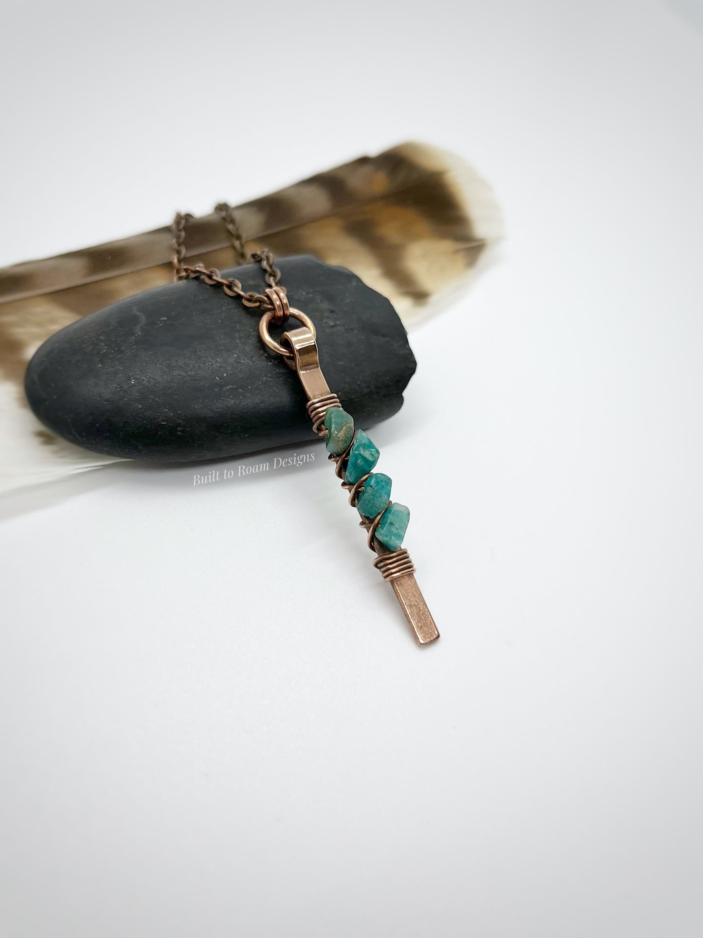 Copper bar necklace with teal amazonite chip beads on a rock with white background - side view - Origin