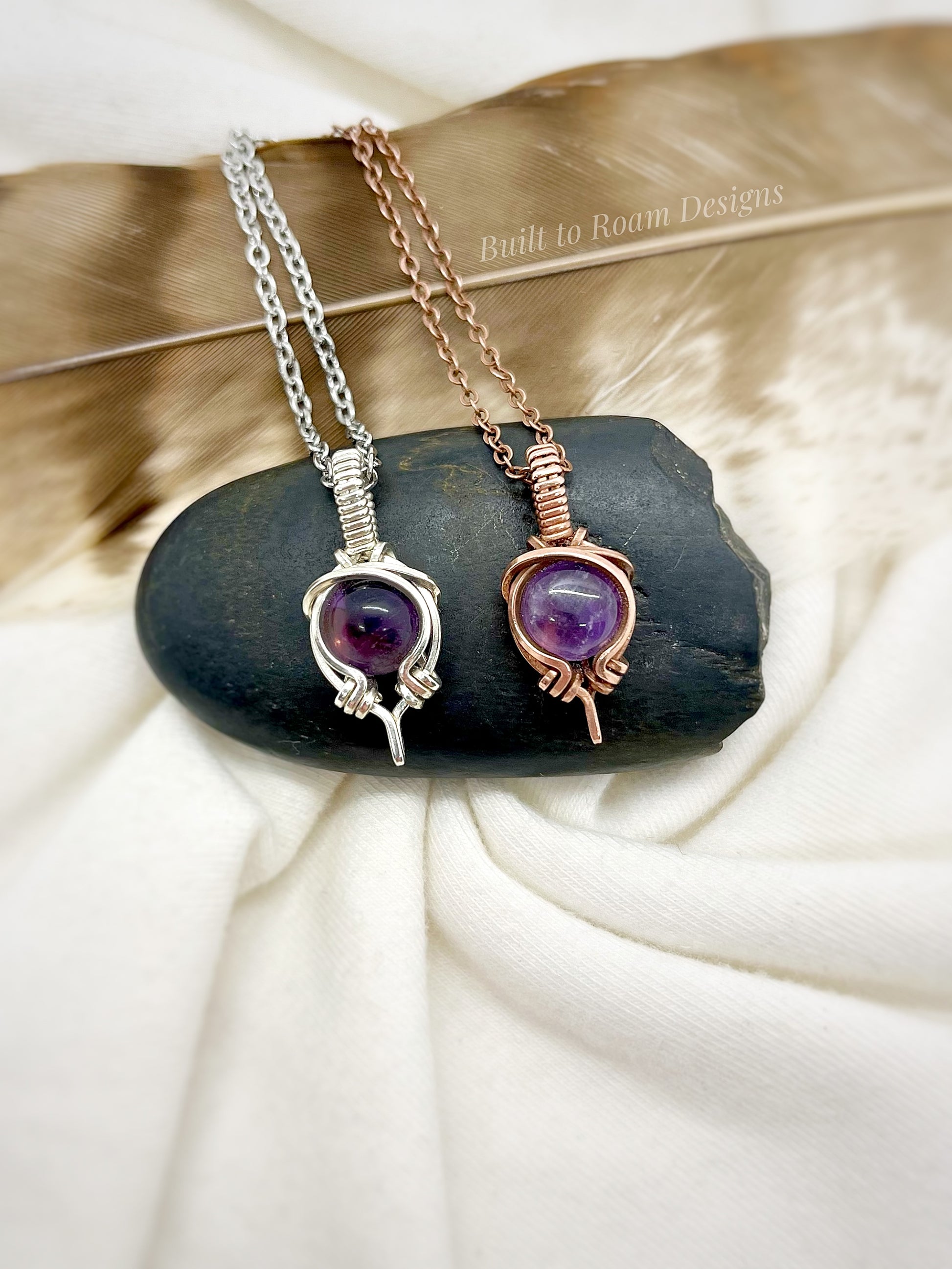 Two necklaces with purple amethyst gemstones on a black stone with a white background