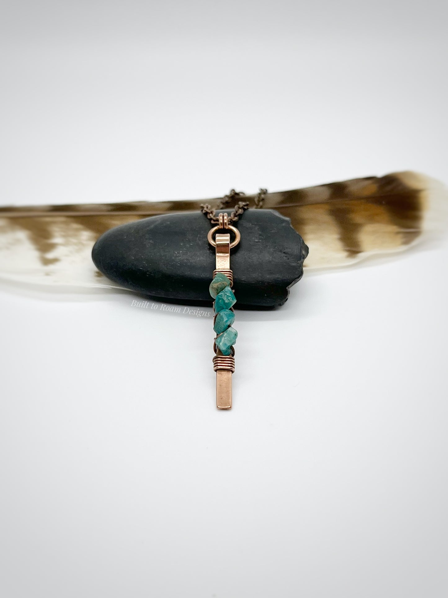 Copper bar necklace with teal amazonite chip beads on a rock with white background - side view - Origin
