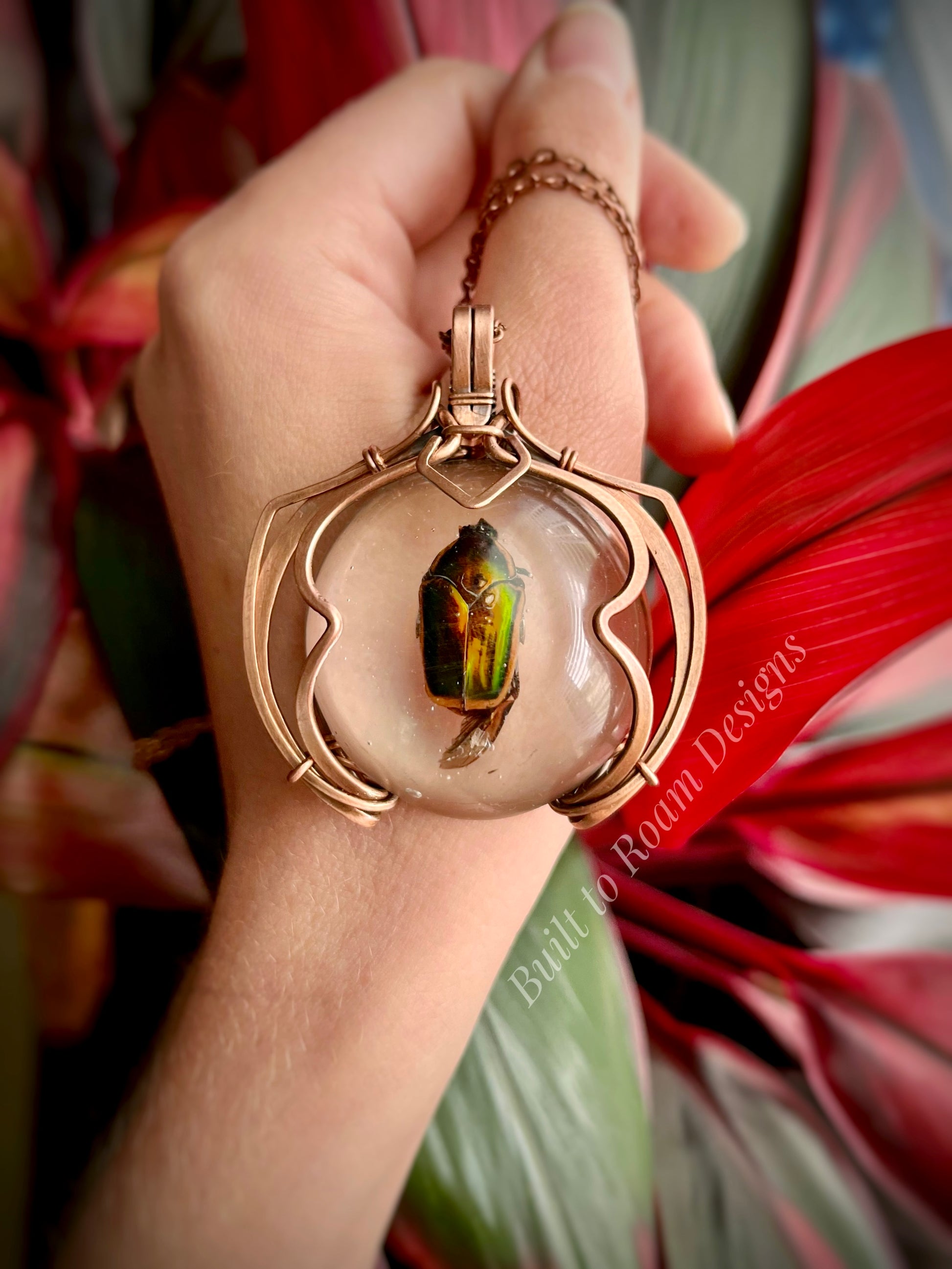 Hand holding a copper pendant with a real, ethically sourced green June Bug in resin - front view - Marty