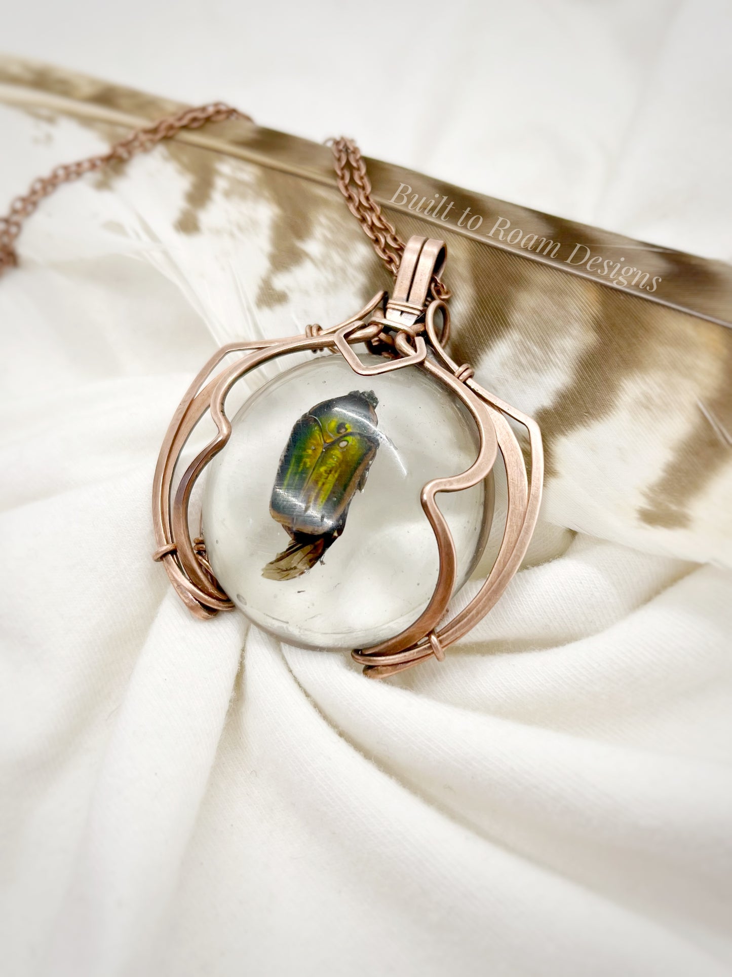Copper pendant with a real, ethically sourced green June Bug in resin on a white fabric background - side view - Marty