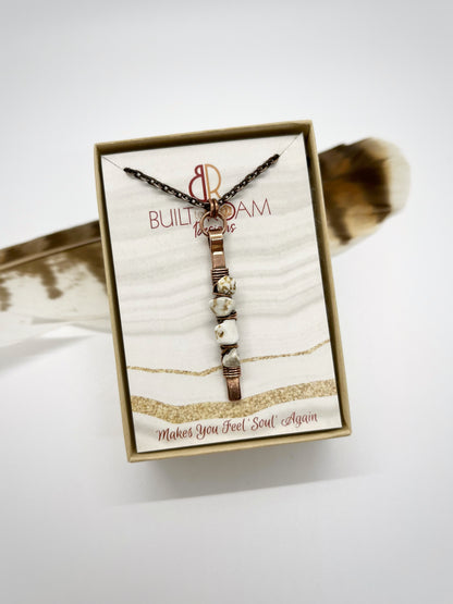 Hand holding a copper bar necklace with white turquoise chip beads in a Built to Roam Designs jewelry box - front view - Horizon