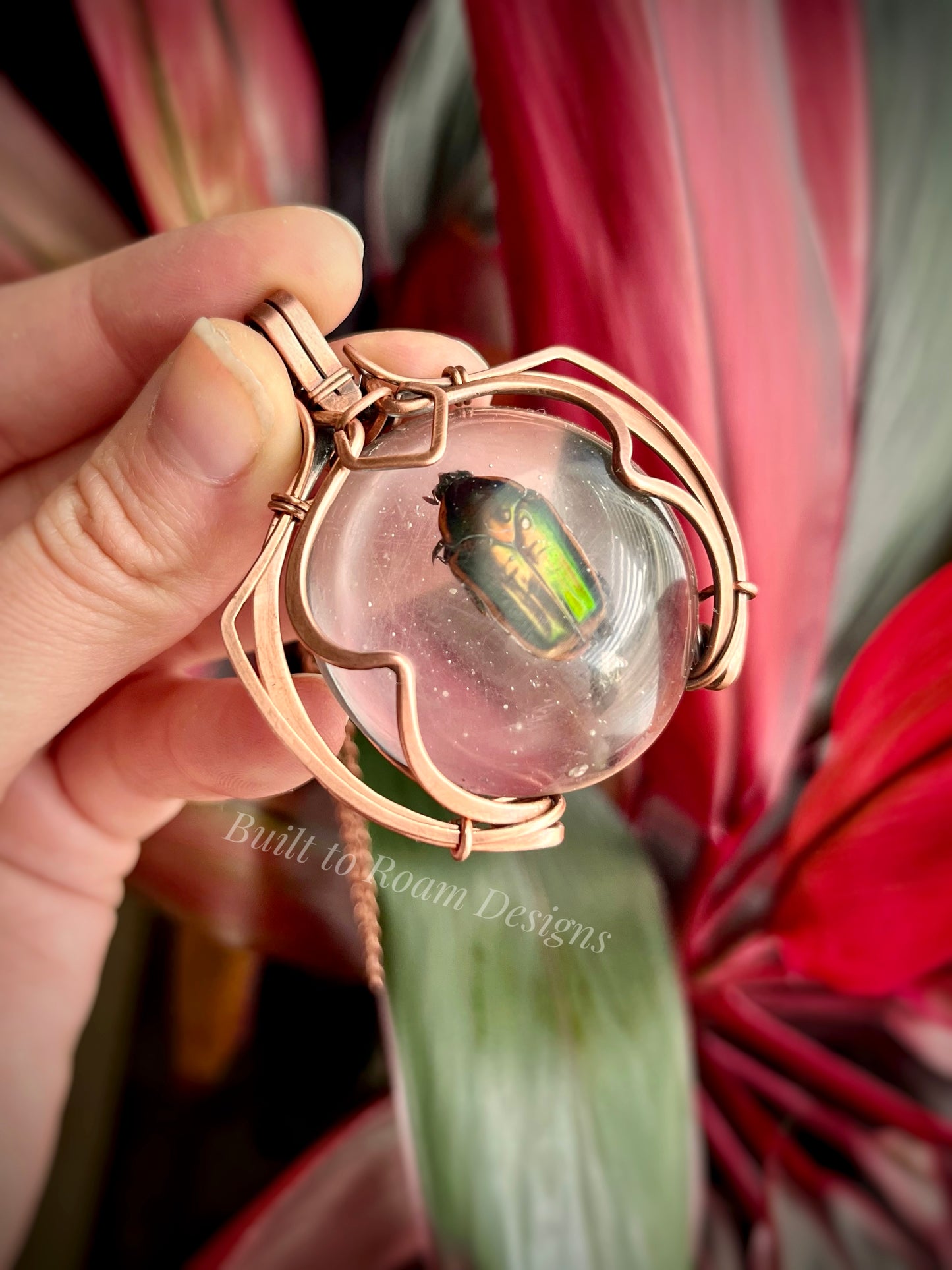 Hand holding a copper pendant with a real, ethically sourced green June Bug in resin - side view - Marty