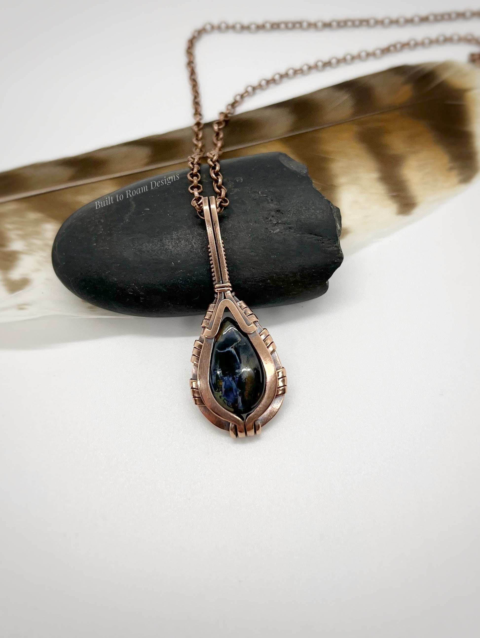 Necklace with a teardrop-shaped pietersite pendant in copper on a white background