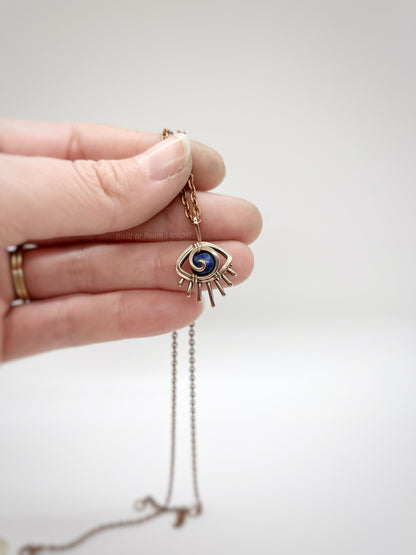 Copper eye-shaped pendant necklace with a blue Sodalite gemstone against a white background - front view - Insight