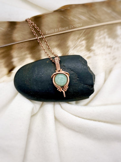 Copper Necklace with a green aventurine gemstone pendant on a black stone with a white fabric background