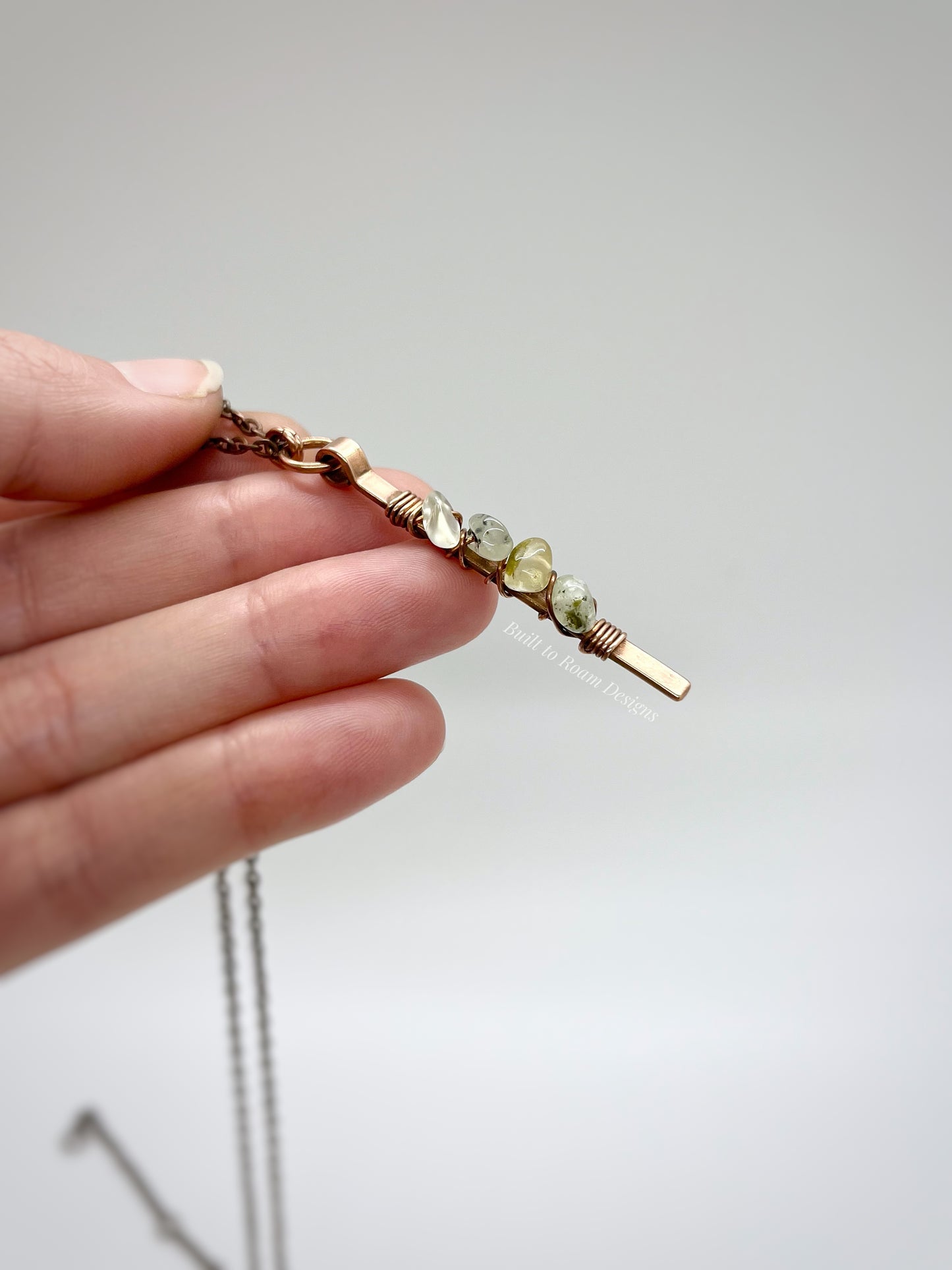 Hand holding a Copper bar necklace with green prehnite chip beads with white background - side view - Thrive 