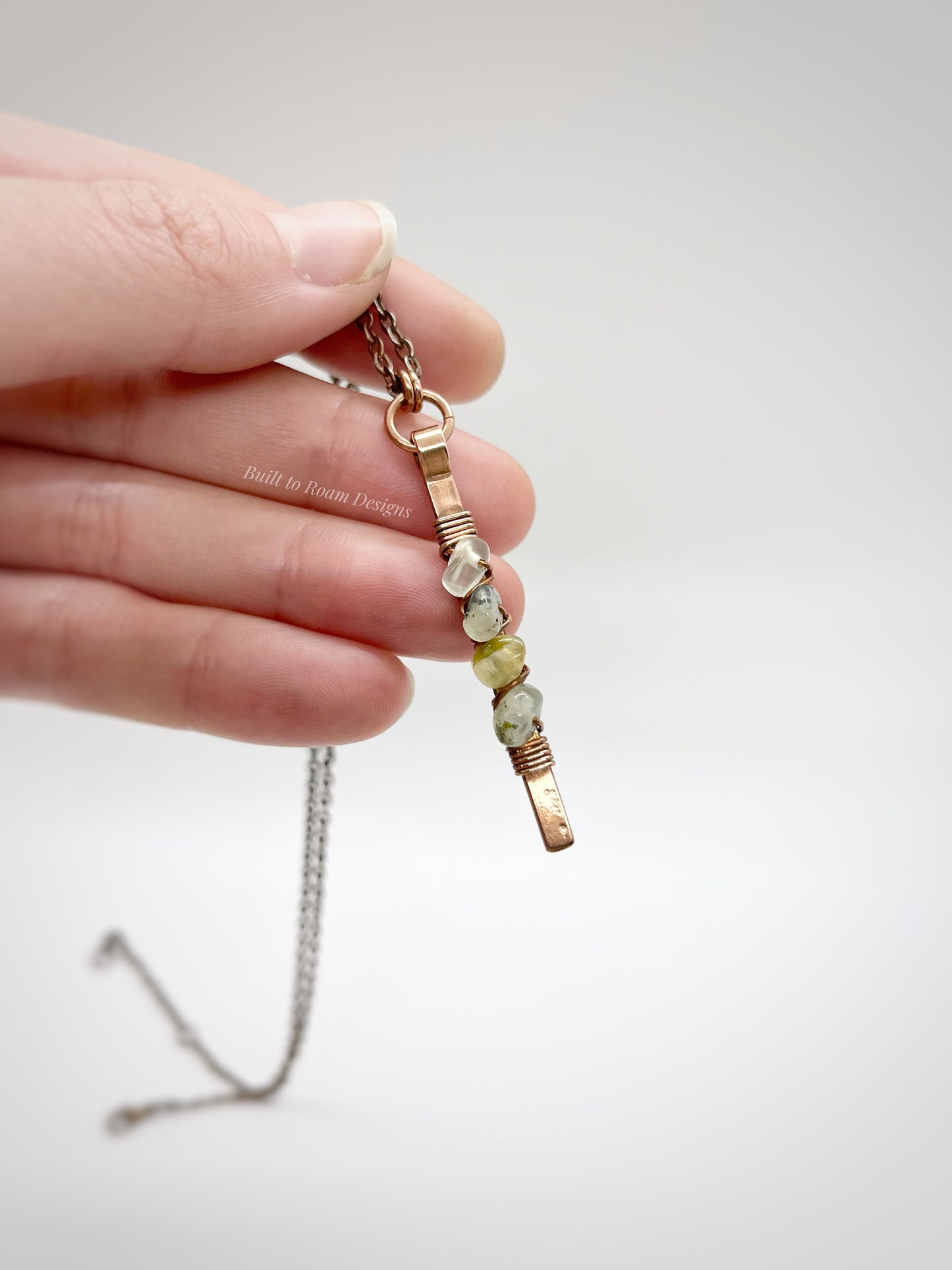 Hand holding a Copper bar necklace with green prehnite chip beads with white background - front view - Thrive 