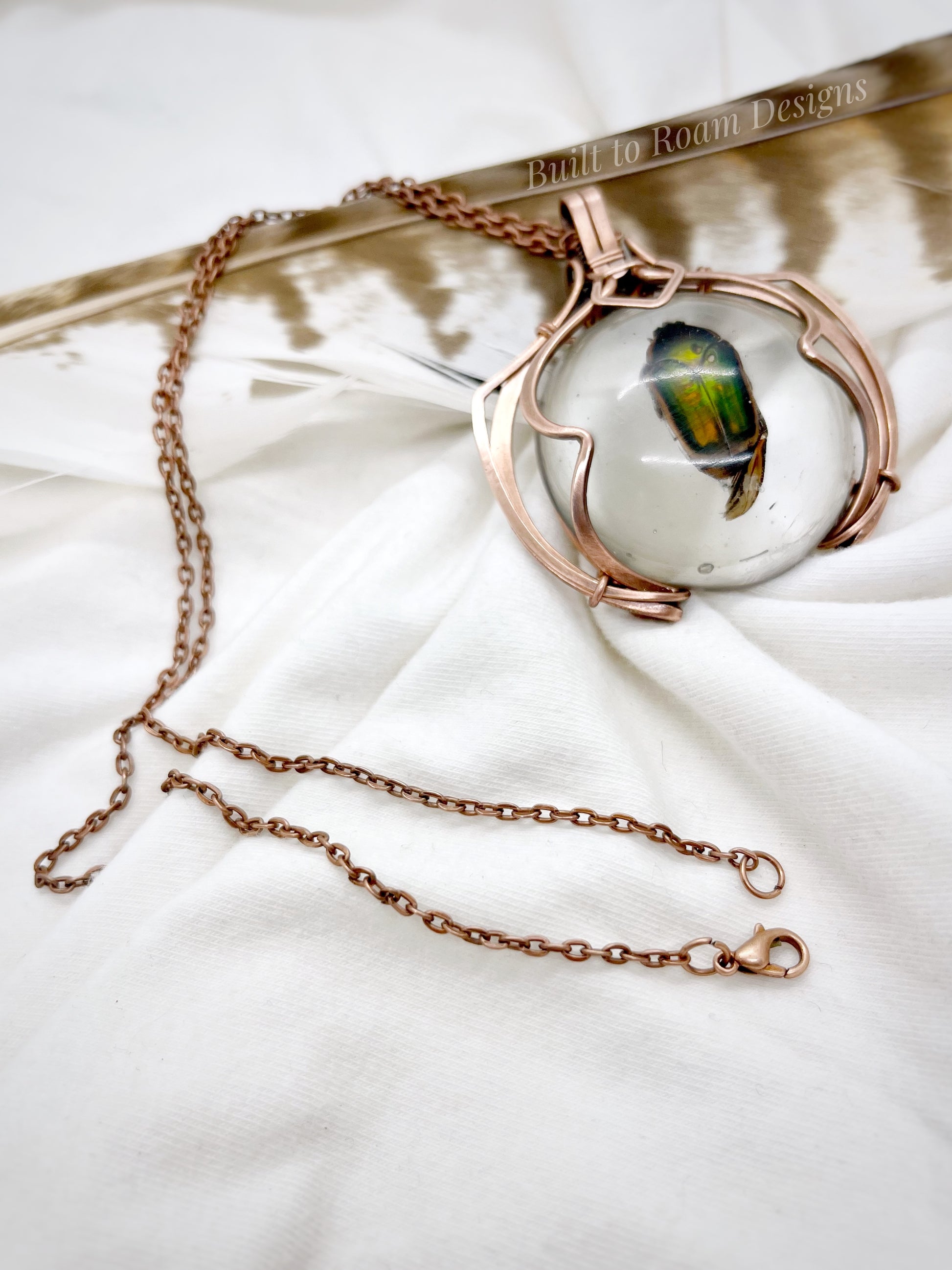 Copper necklace with a real, ethically sourced green June Bug in resin pendant on a white fabric background - side view - Marty