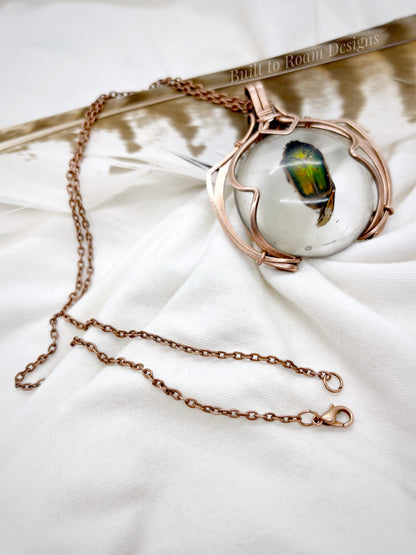 Copper necklace with a real, ethically sourced green June Bug in resin pendant on a white fabric background - side view - Marty