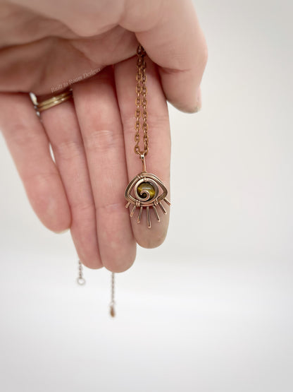 Hand holding a Copper eye-shaped pendant necklace with a golden Tiger’s Eye gemstone against a white background - front view - Guardian