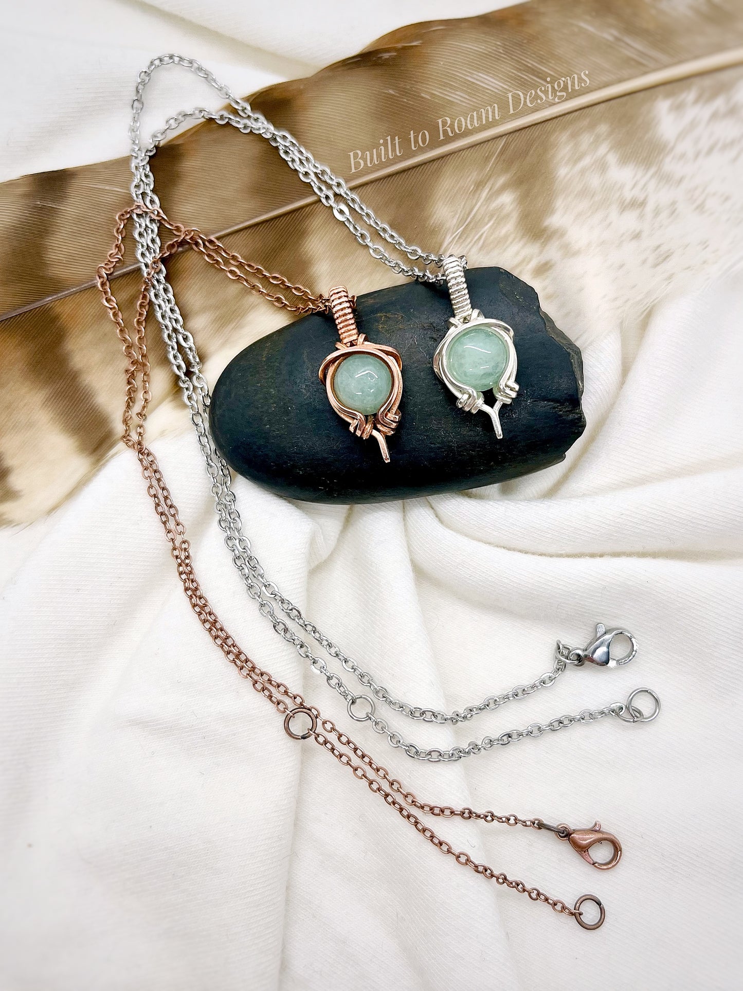 Two necklaces with green aventurine gemstone pendant on a dark stone surface