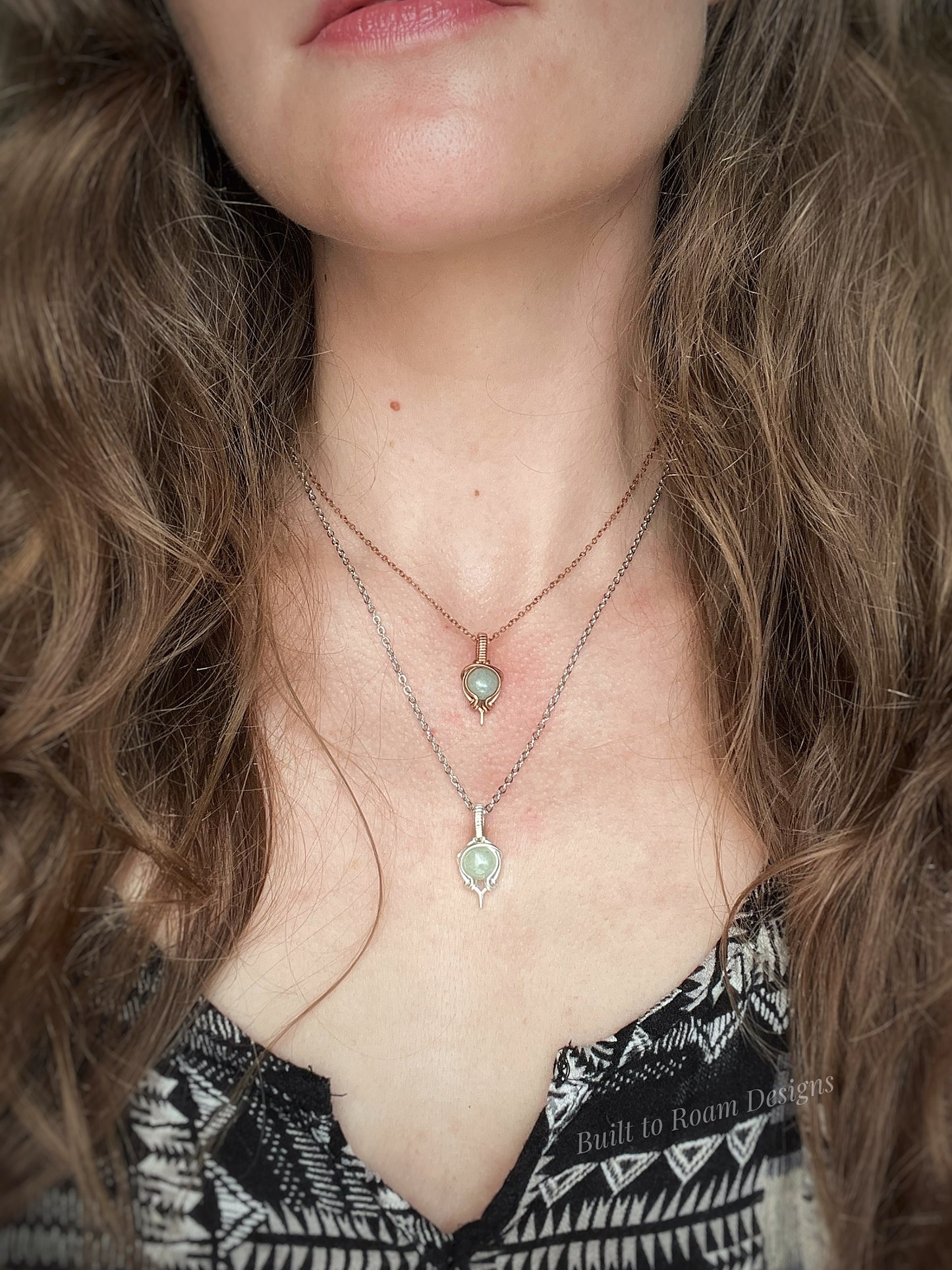 Close-up of a person wearing two necklaces with green aventurine pendants.