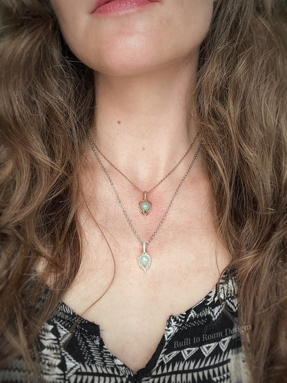 Close-up of a person wearing two necklaces with green aventurine pendants.