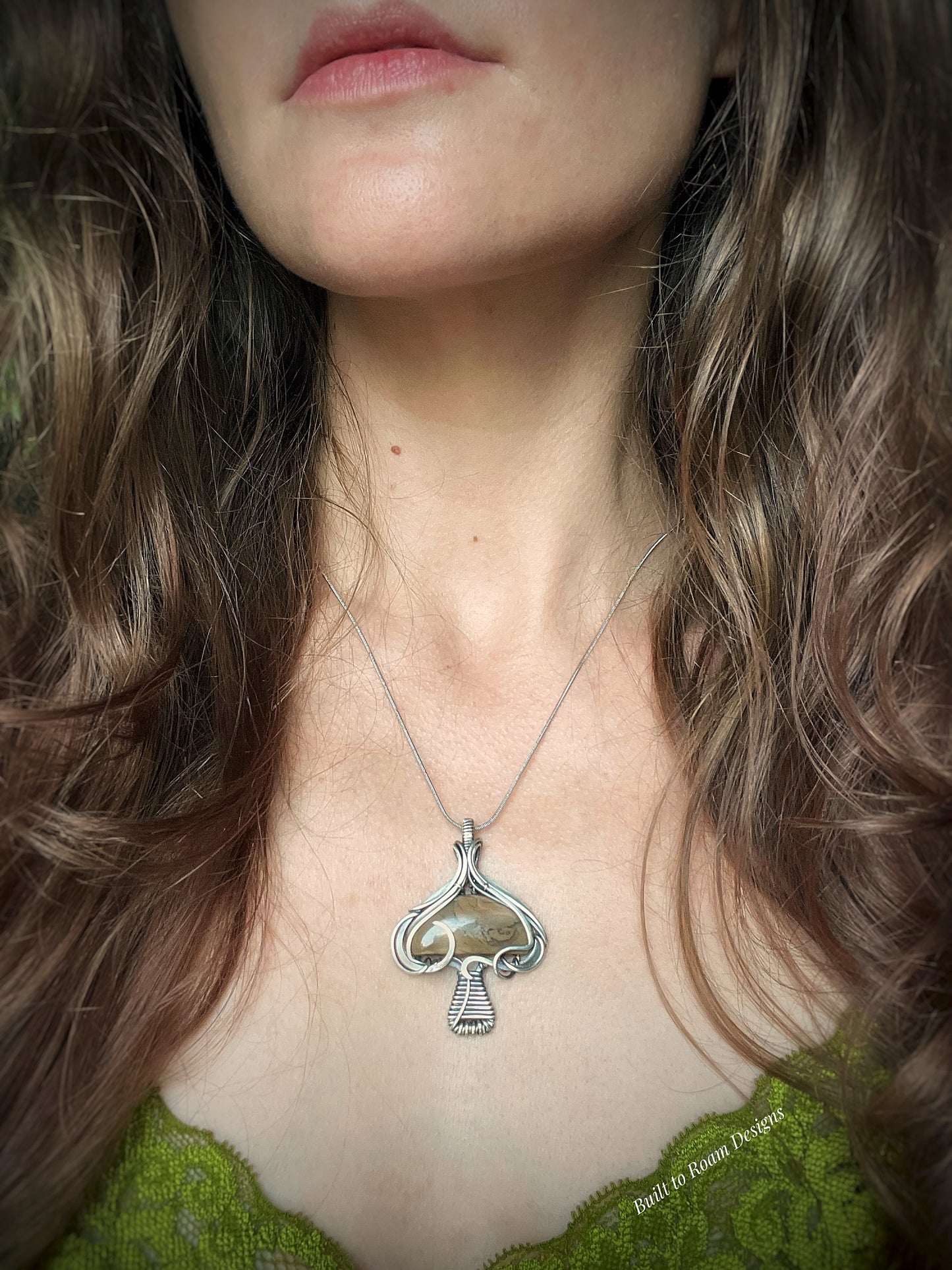 Silver mushroom-shaped pendant with a brown Mookaite Jasper gemstone on a person - front view