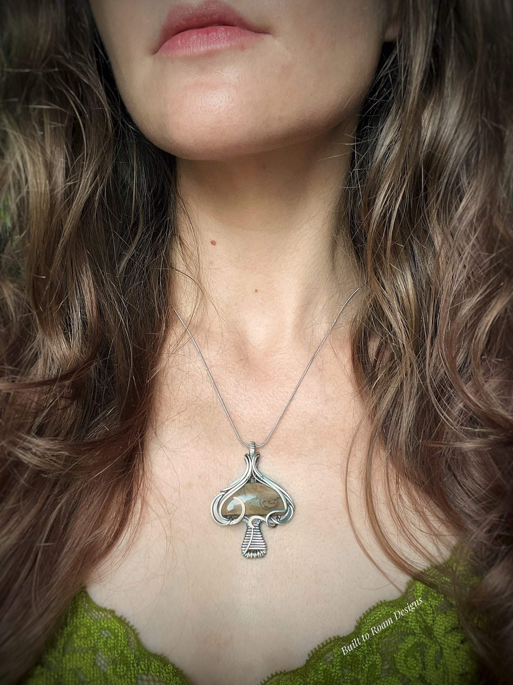 Silver mushroom-shaped pendant with a brown Mookaite Jasper gemstone on a person - front view