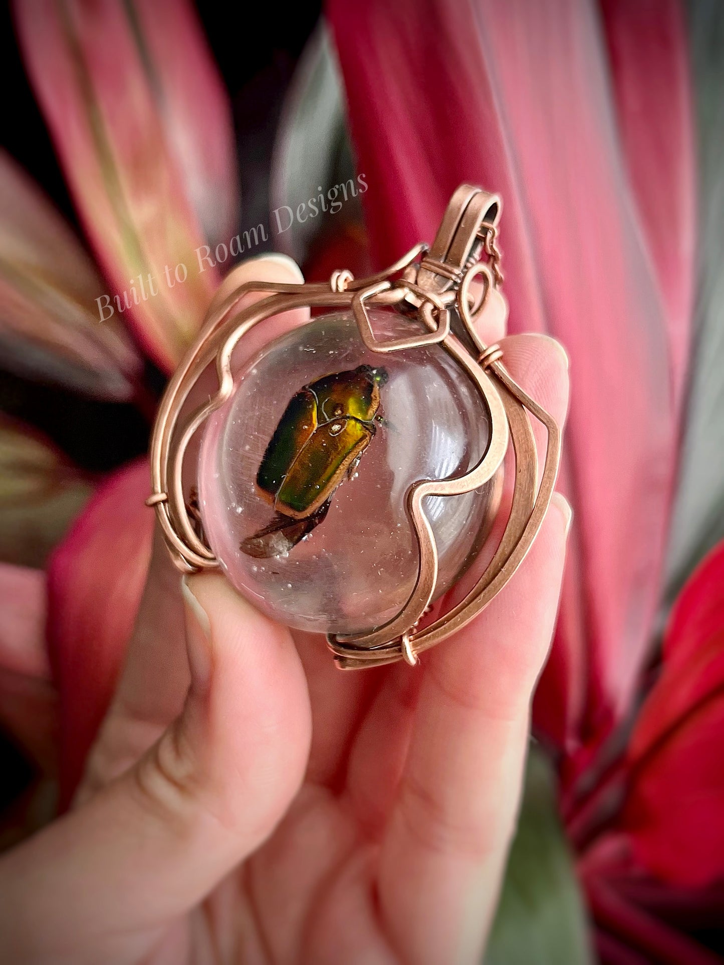 Hand holding a copper pendant with a real, ethically sourced green June Bug in resin - side view - Marty