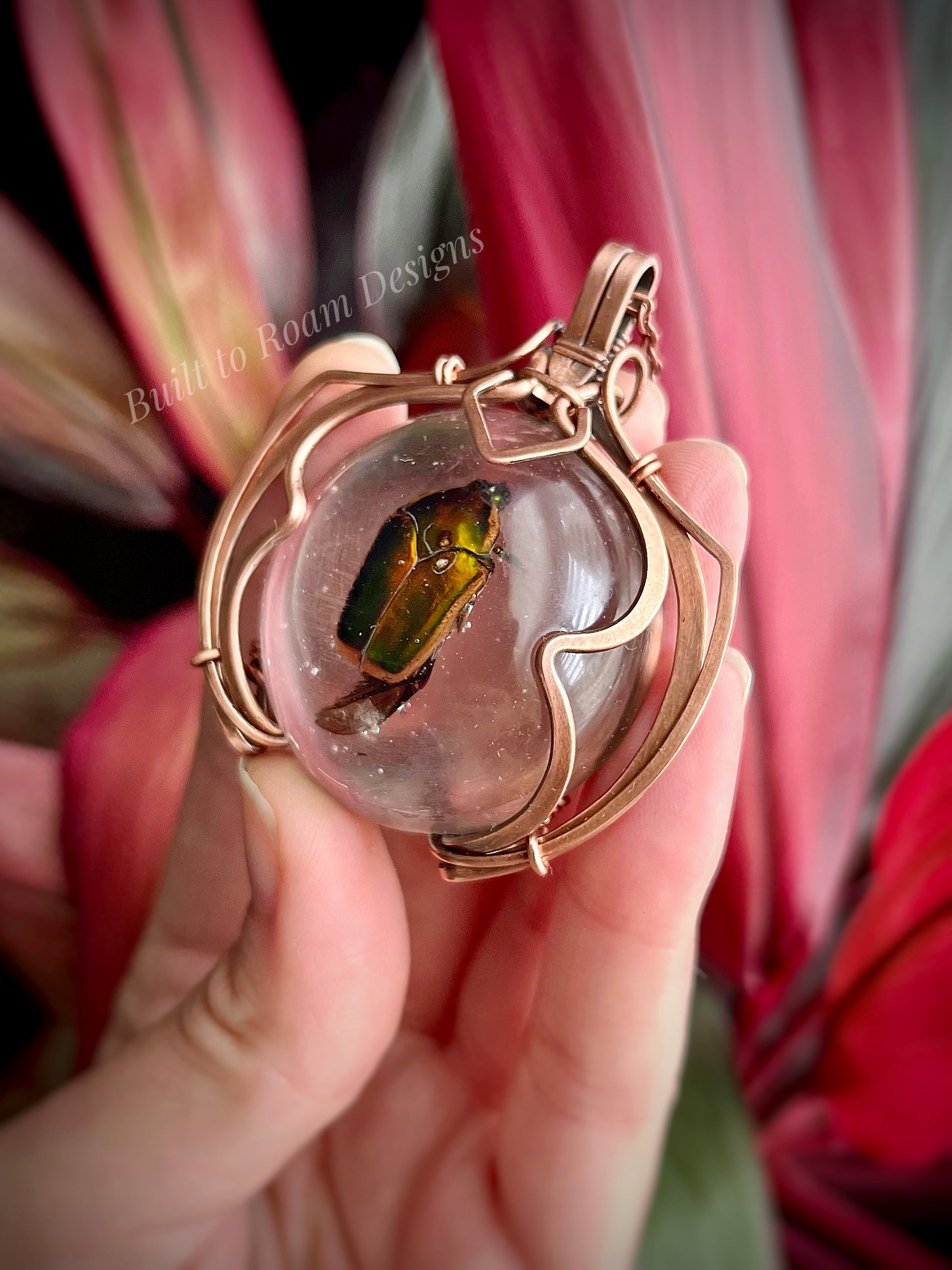 Hand holding a copper pendant with a real, ethically sourced green June Bug in resin - side view - Marty