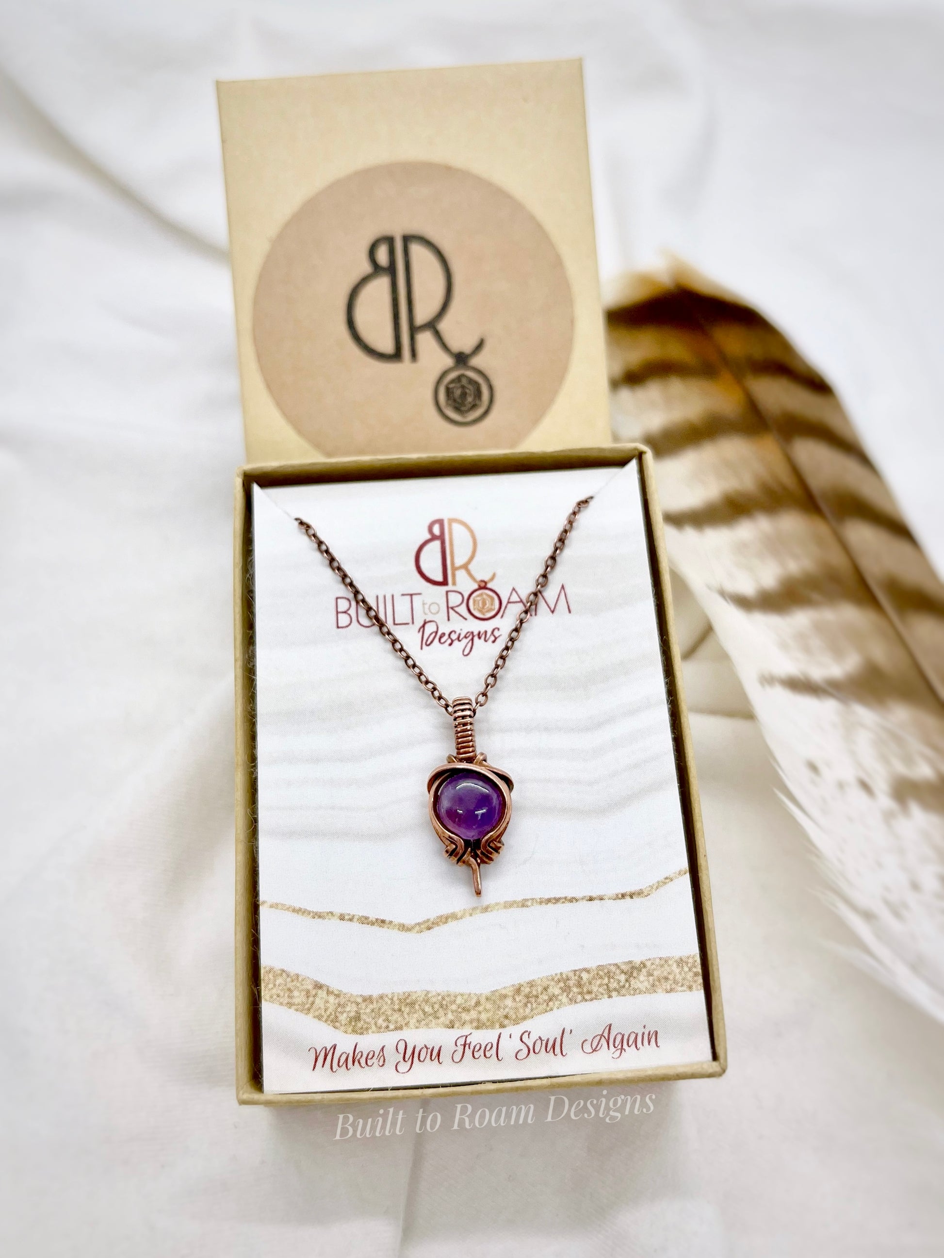 Copper Necklace with purple amethyst pendant in a 'Built to Roam Designs' box on a white background