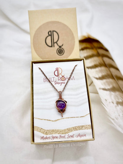 Copper Necklace with purple amethyst pendant in a 'Built to Roam Designs' box on a white background