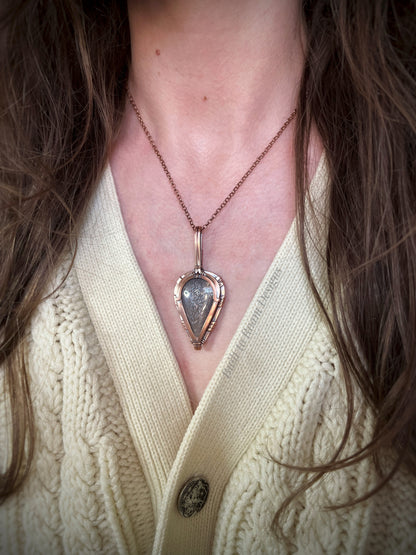 Lattice sunstone in copper pendant worn by a person in a cream sweater