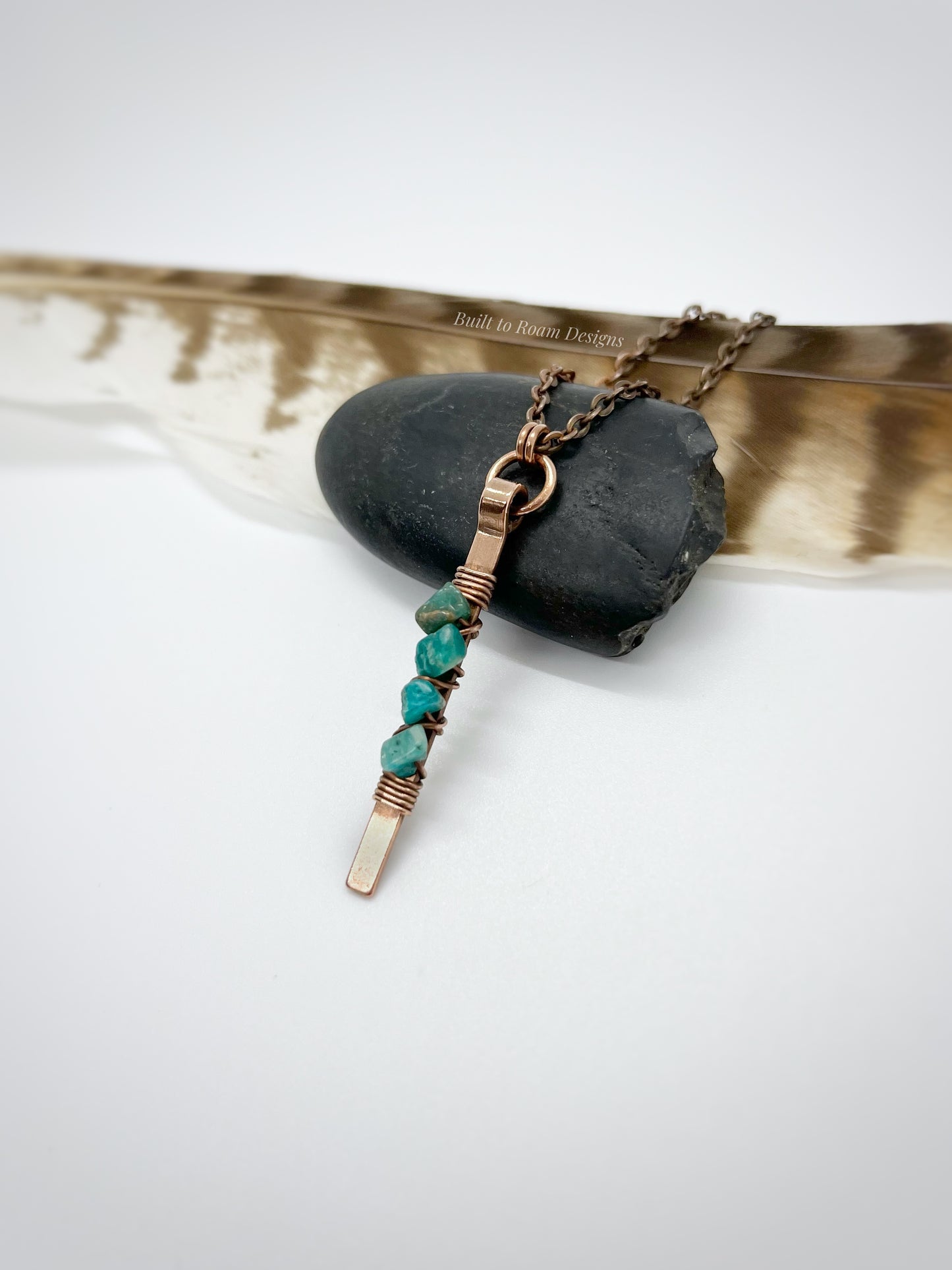 Copper bar necklace with teal amazonite chip beads on a rock with white background - side view - Origin