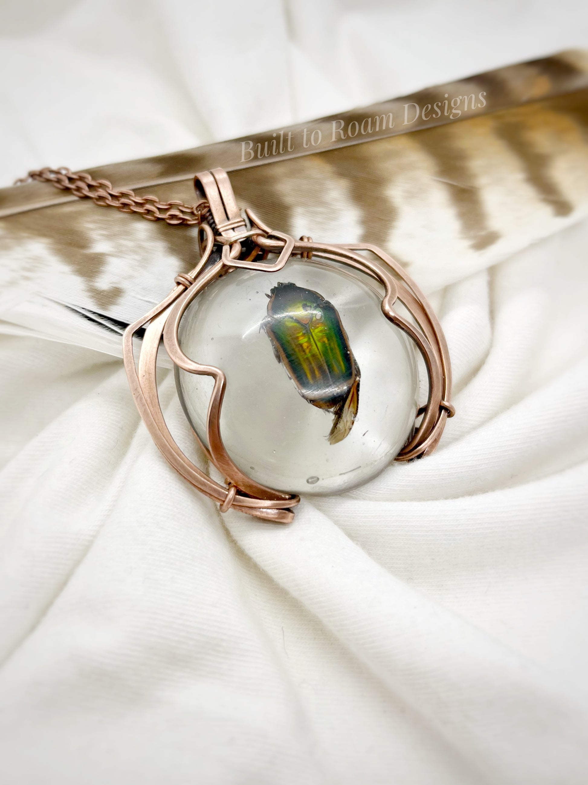 Copper pendant with a real, ethically sourced green June Bug in resin on a white fabric background - side view - Marty