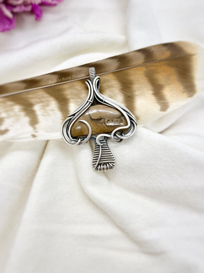 Silver mushroom-shaped pendant with a brown Mookaite Jasper gemstone on a white fabric background