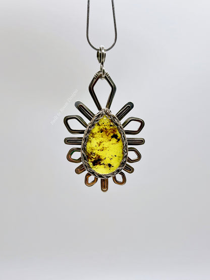 Front view of a silver and bronze star-burst pendant with a golden amber gemstone on a necklace with a white background - Liora