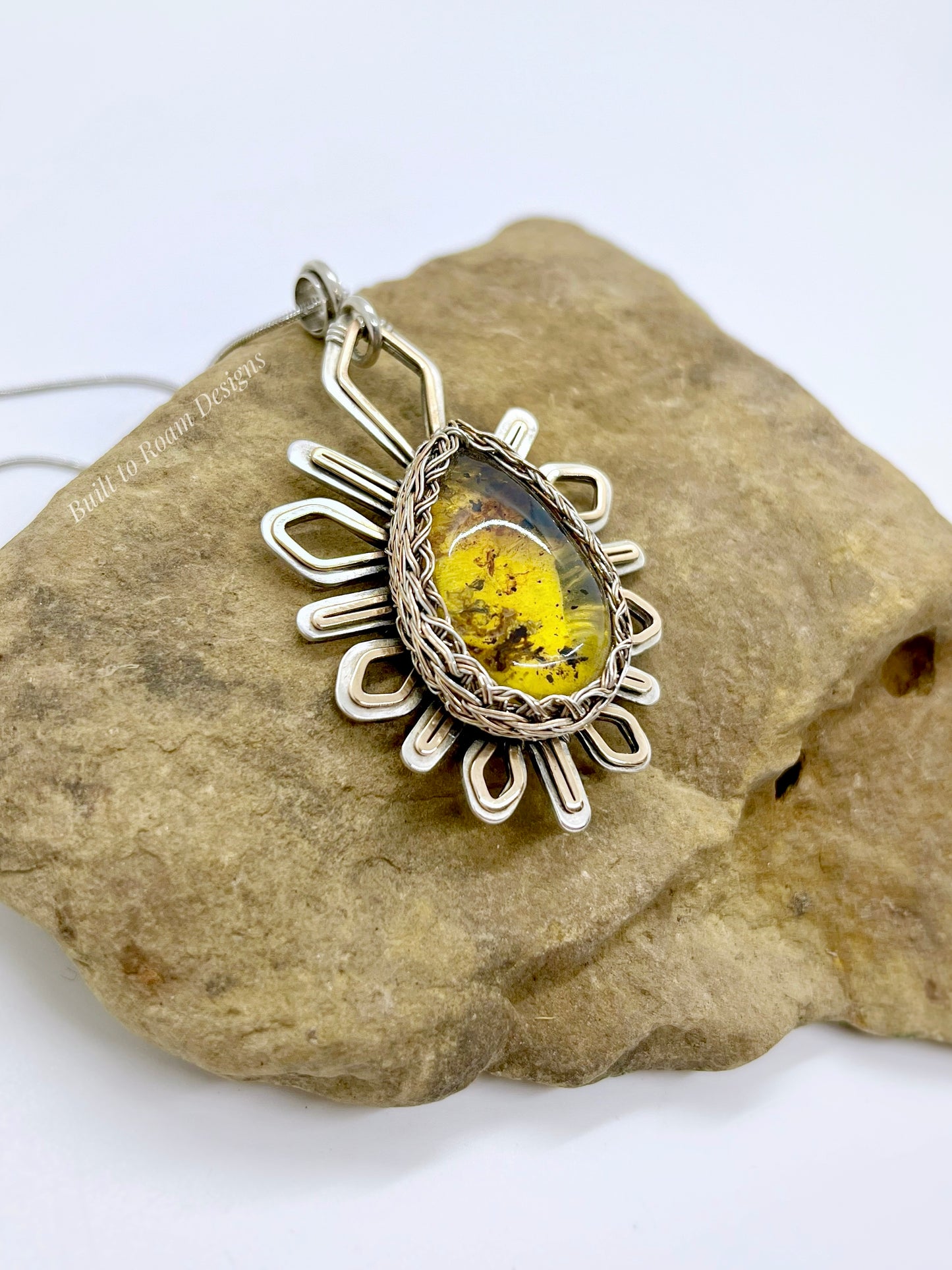 Silver and bronze pendant with a golden amber stone on a rock - Liora