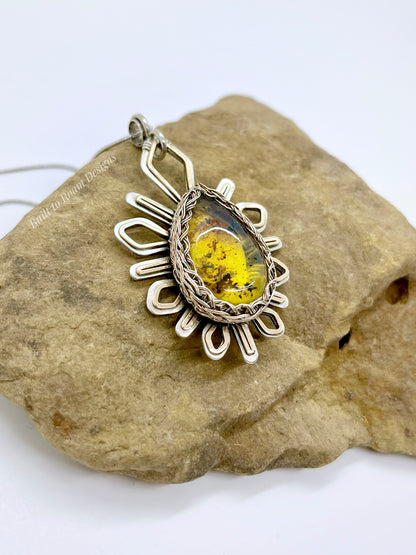 Silver and bronze pendant with a golden amber stone on a rock - Liora