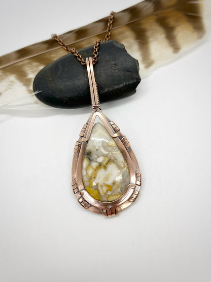 Teardrop-shaped pendant with a wild horse jasper stone in copper on a white background