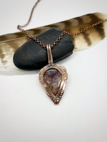 Necklace with a pendant featuring a purple moss agate stone in copper on a white background